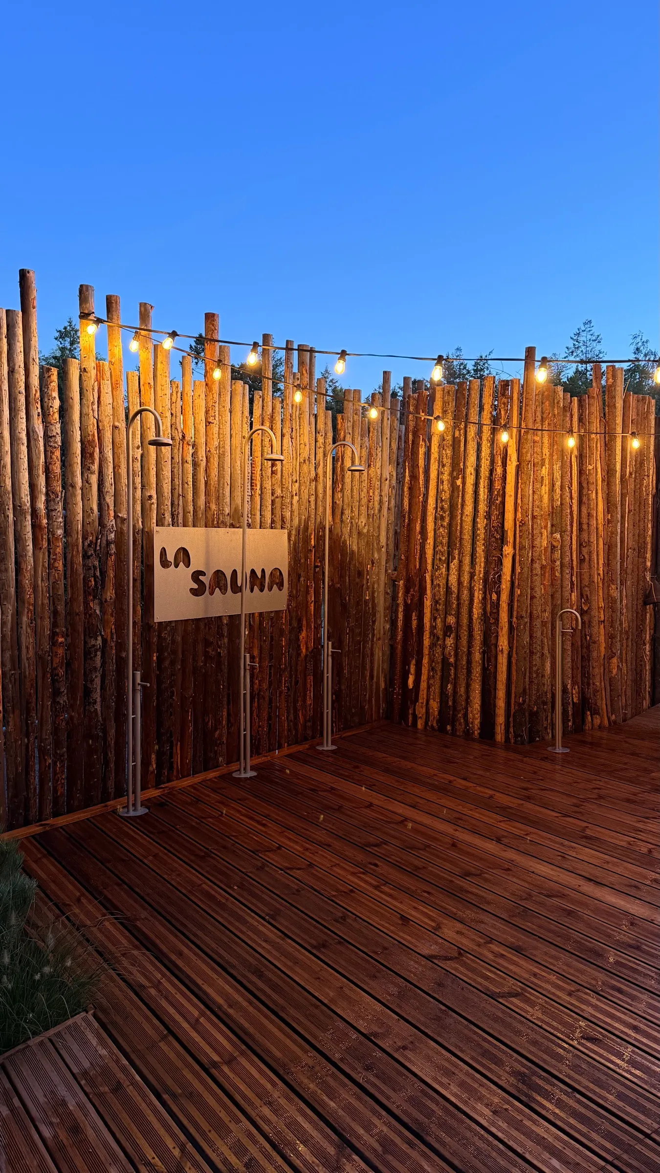 Udendørs brusere ved træhegnet med La Sauna-skiltet i Silkeborg