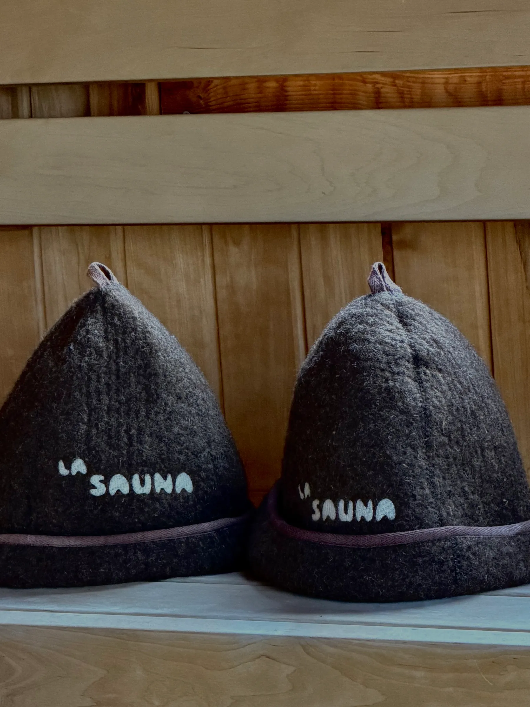To La Sauna-saunahuer i mørk uld på saunaens bænk